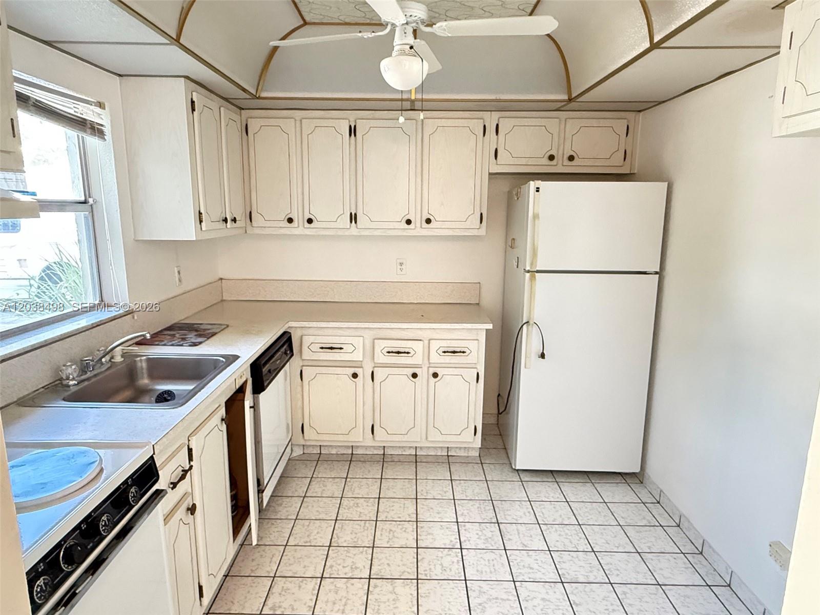 A kitchen features white cabinets, a white refrigerator, a tiled floor, and a ceiling fan — 417 SW Natura Ave # A, Deerfield Beach FL 33441, DEERFIELD BEACH, FL
