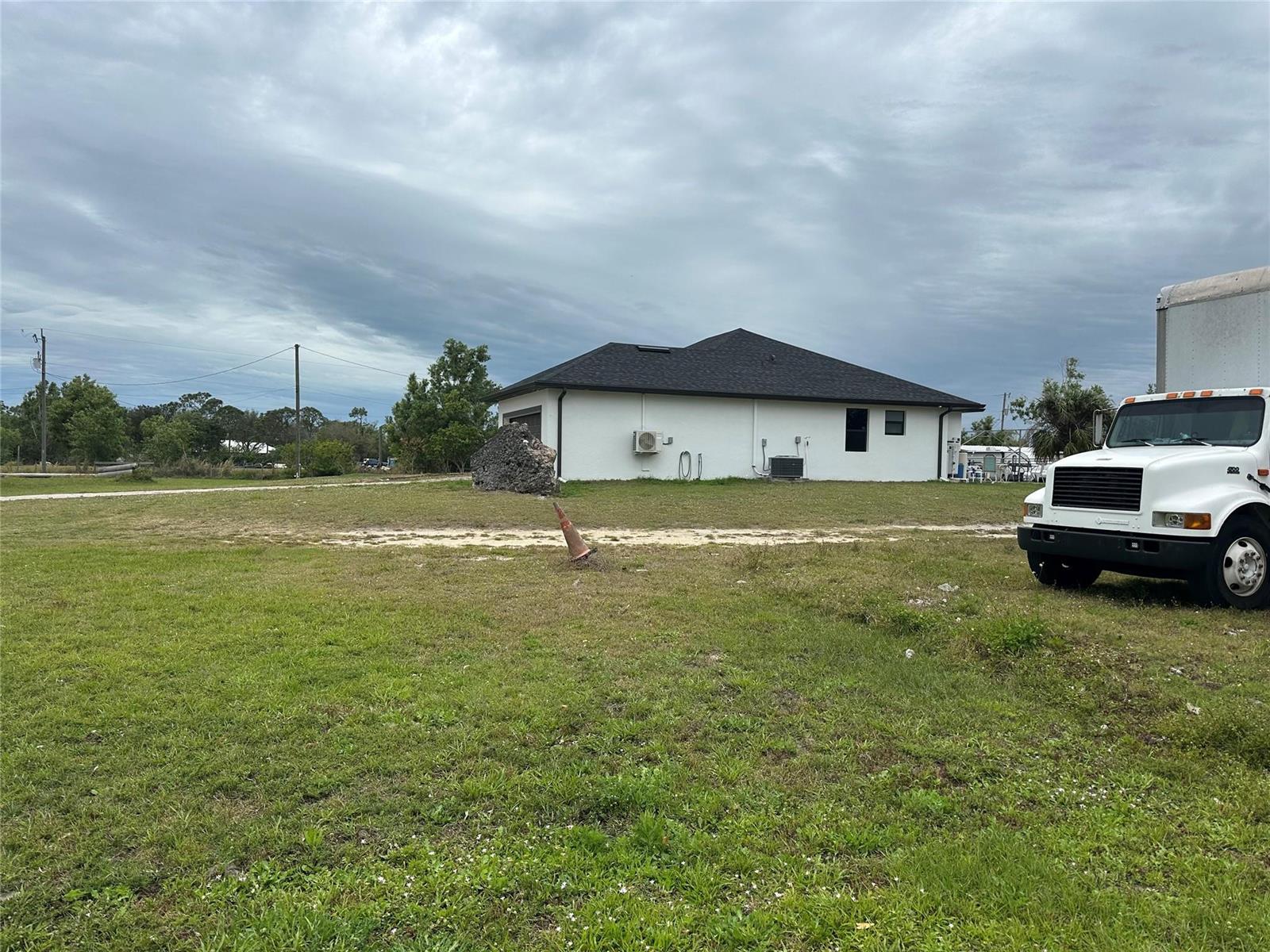 A white house with a dark roof sits on a large, grassy lot — 3401 Sand Road, Cape Coral FL 33993, CAPE CORAL, FL