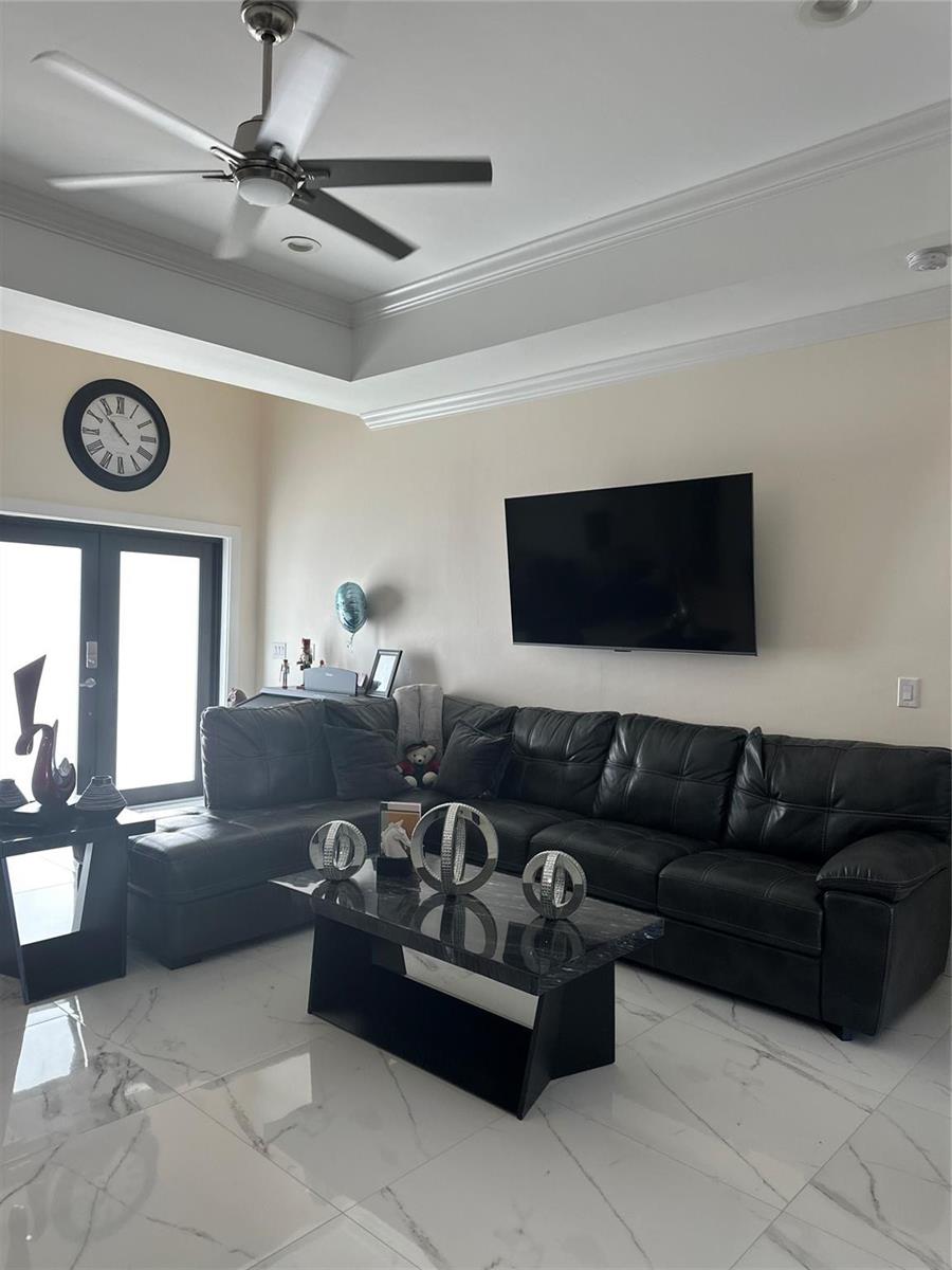 A living room features a black sectional sofa, a coffee table, and a wall-mounted television — 3401 Sand Road, Cape Coral FL 33993, CAPE CORAL, FL