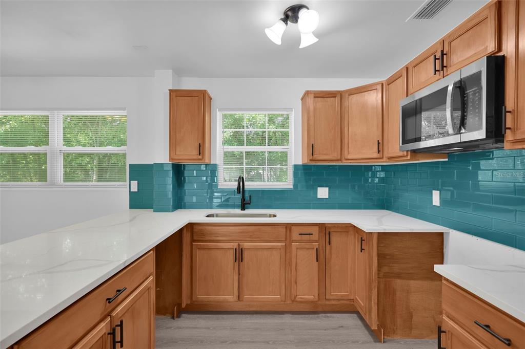 A kitchen with wood cabinets, teal subway tile backsplash, white countertops, and stainless steel appliances — 1110 BUSAC AVENUE, JACKSONVILLE, FL
