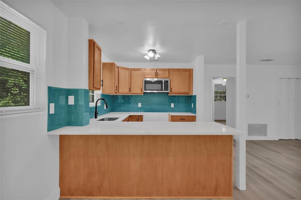 A kitchen features wood cabinets, a teal subway tile backsplash, and a white countertop — 1110 BUSAC AVENUE, JACKSONVILLE, FL