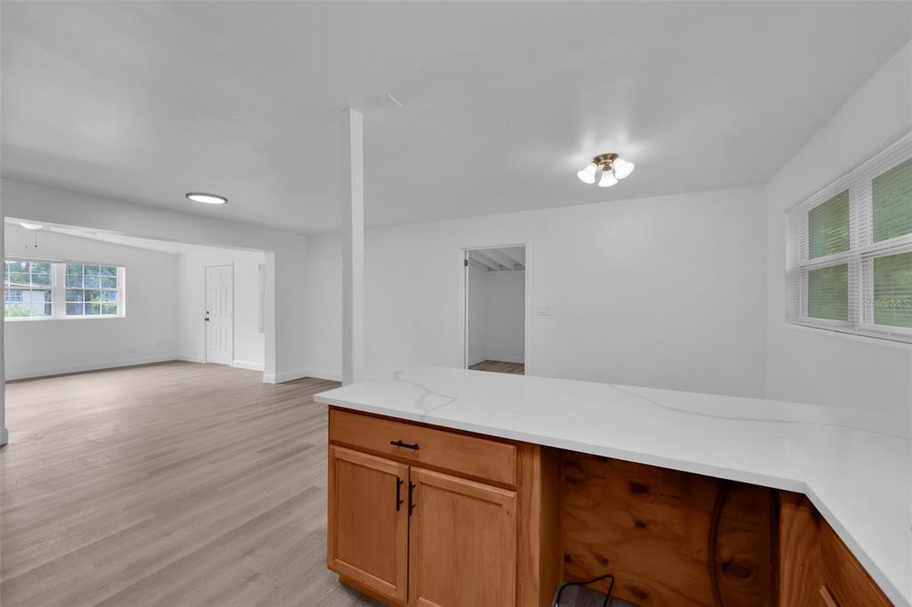 A kitchen island with a white countertop overlooks a living area with light-colored flooring — 1110 BUSAC AVENUE, JACKSONVILLE, FL