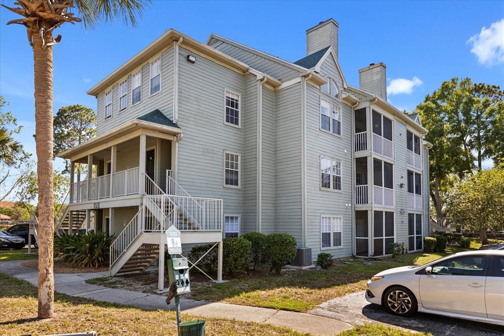 A three-story apartment building with light green siding, white railings, and screened-in balconies — 6178 WESTGATE DRIVE UNIT 101, ORLANDO, FL