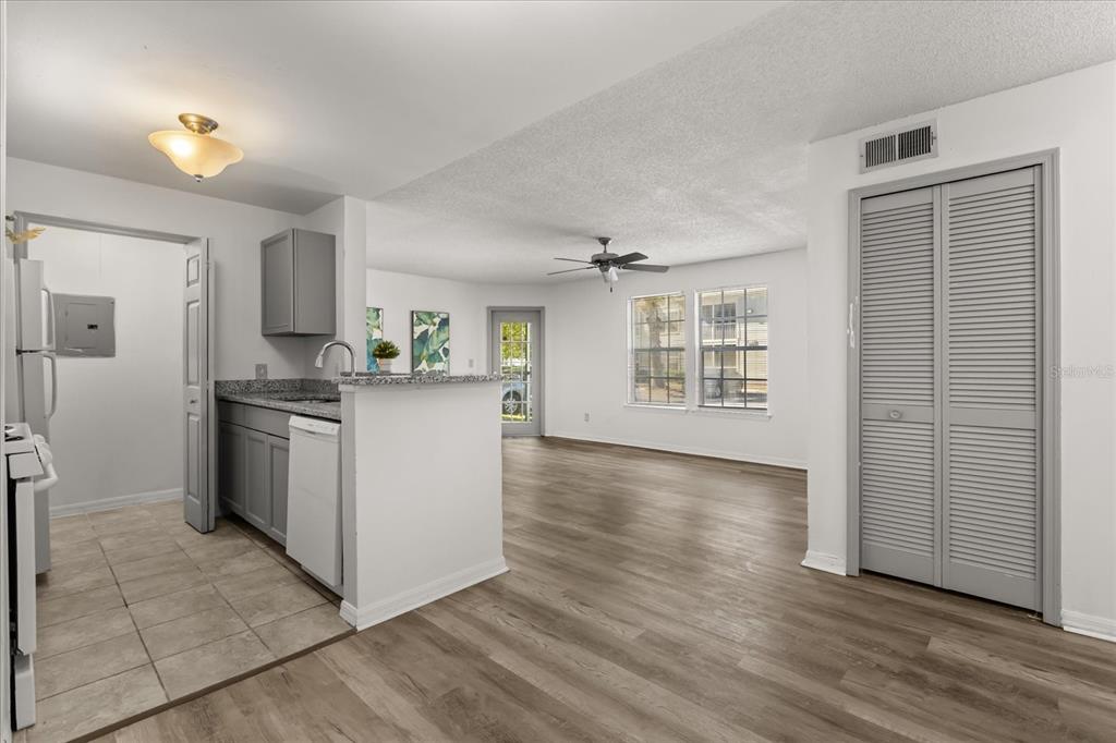 An open-concept kitchen with grey cabinets and a living area with wood-look flooring — 6178 WESTGATE DRIVE UNIT 101, ORLANDO, FL