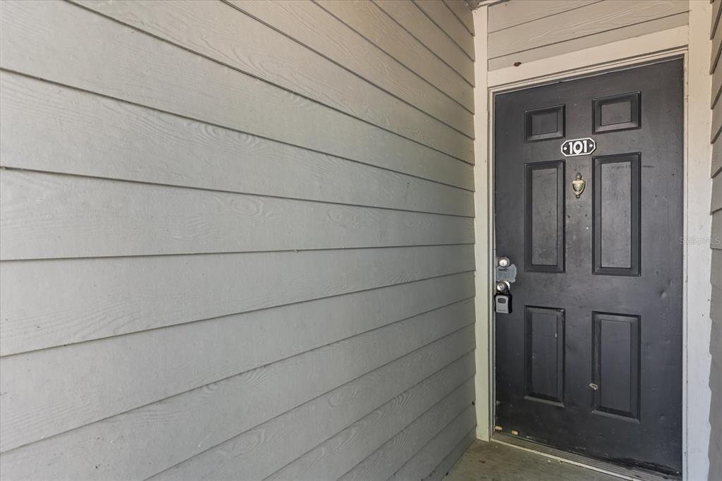 A dark gray front door with the number 101 is set against light gray horizontal siding — 6178 WESTGATE DRIVE UNIT 101, ORLANDO, FL