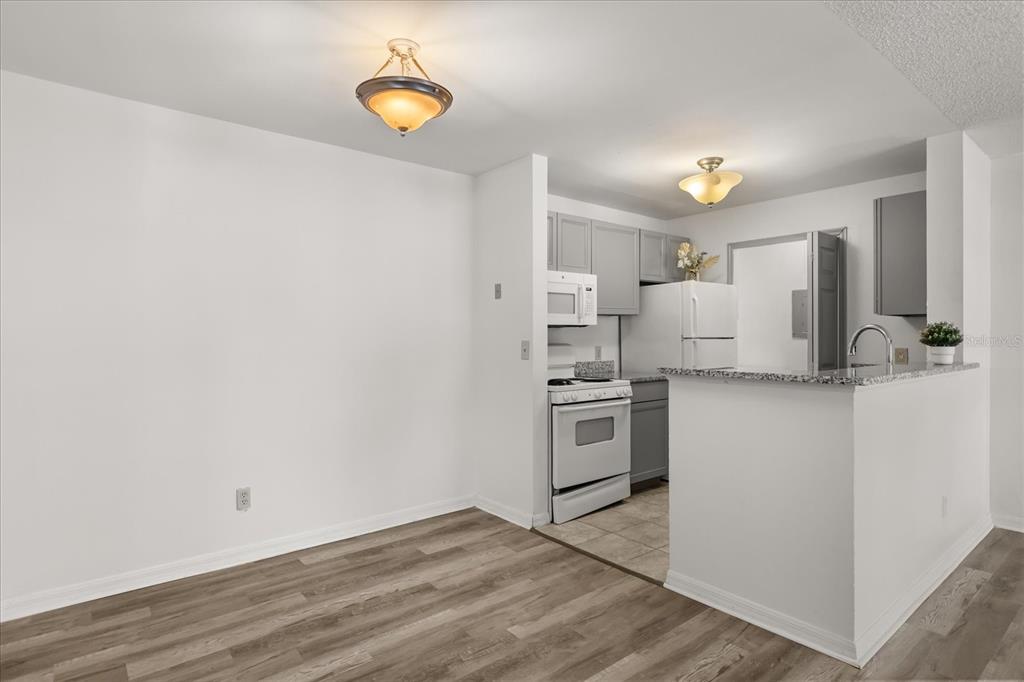 A dining area with wood-look flooring opens to a kitchen featuring gray cabinets and appliances — 6178 WESTGATE DRIVE UNIT 101, ORLANDO, FL