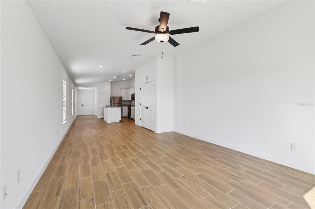 An open-concept living area features light wood-look tile flooring, white walls, and a ceiling fan — 5223 CAP ROAD, BROOKSVILLE, FL