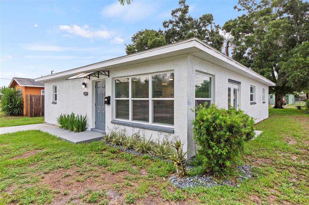 A white stucco house with a grey door and large windows sits on a lawn — 2827 16TH AVENUE S, ST PETERSBURG, FL