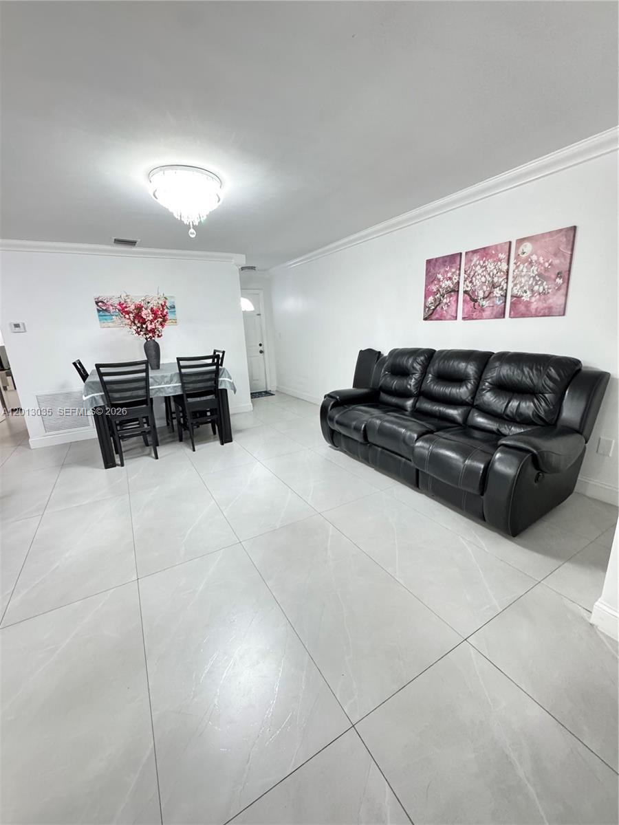 A dining area and living room feature white walls, light tile flooring, and black furniture — 7140 W 15th Ct, Hialeah FL 33014, HIALEAH, FL