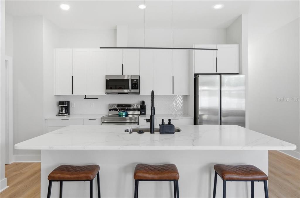 A modern kitchen features white cabinets, a marble-topped island, and stainless steel appliances — 2644 42ND AVENUE N, ST PETERSBURG, FL