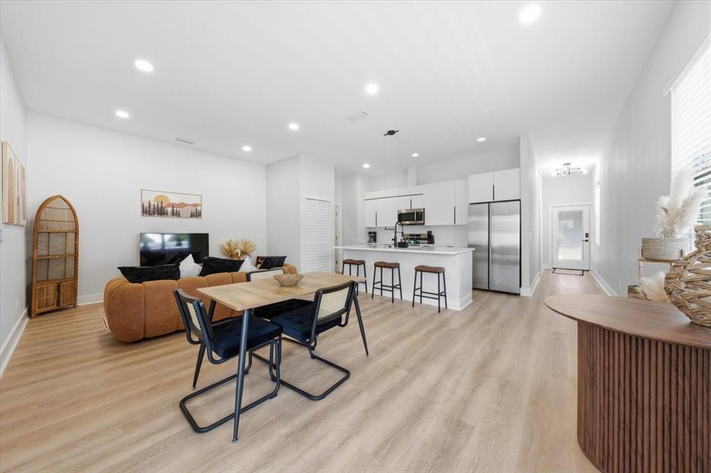 An open-concept living and dining area features light wood flooring, white cabinetry, and modern furniture — 2644 42ND AVENUE N, ST PETERSBURG, FL