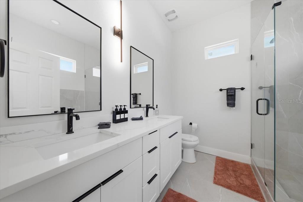 A modern bathroom features a double vanity with white cabinets, black fixtures, and a shower — 2644 42ND AVENUE N, ST PETERSBURG, FL