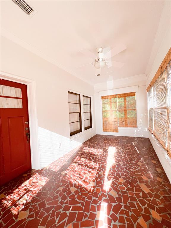 A sunroom features a red mosaic tile floor, a ceiling fan, and a red door — 501 NE 8TH AVENUE, GAINESVILLE, FL