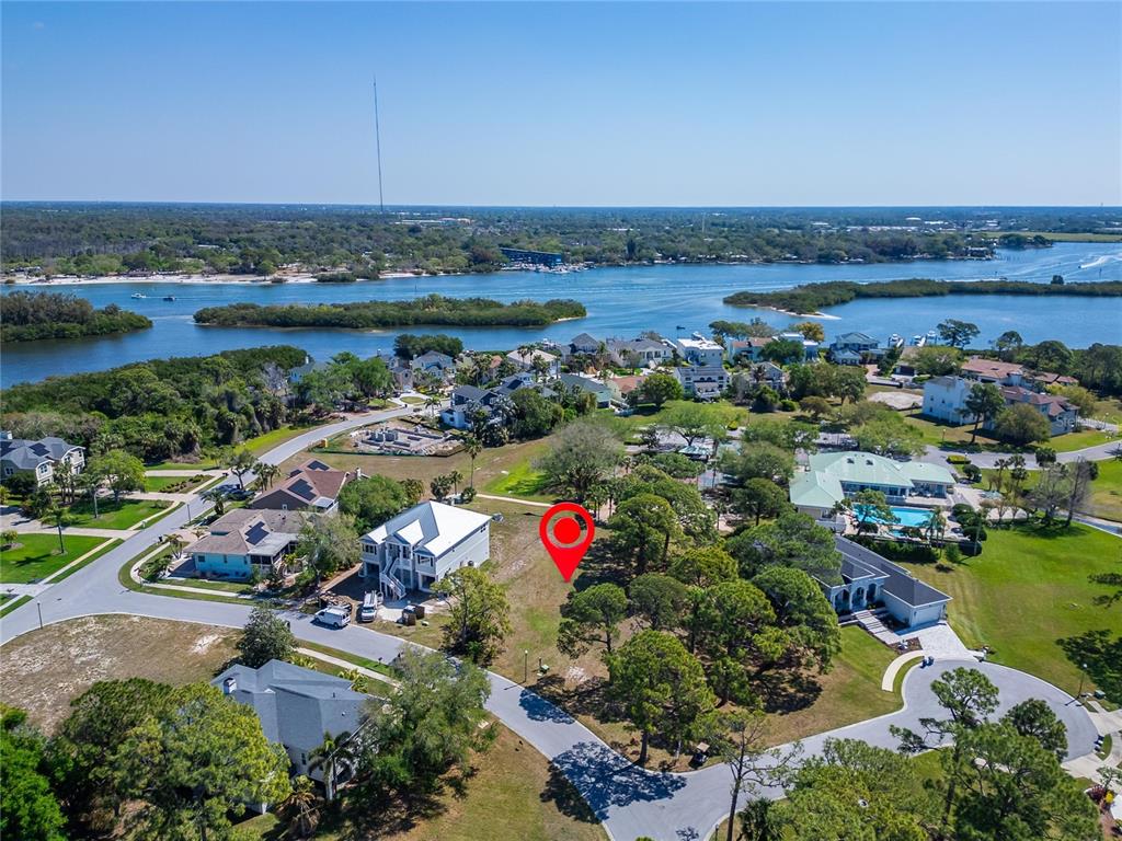 An aerial view shows a vacant, tree-filled residential lot marked by a red pin — HARBOUR WATCH DRIVE, TARPON SPRINGS, FL