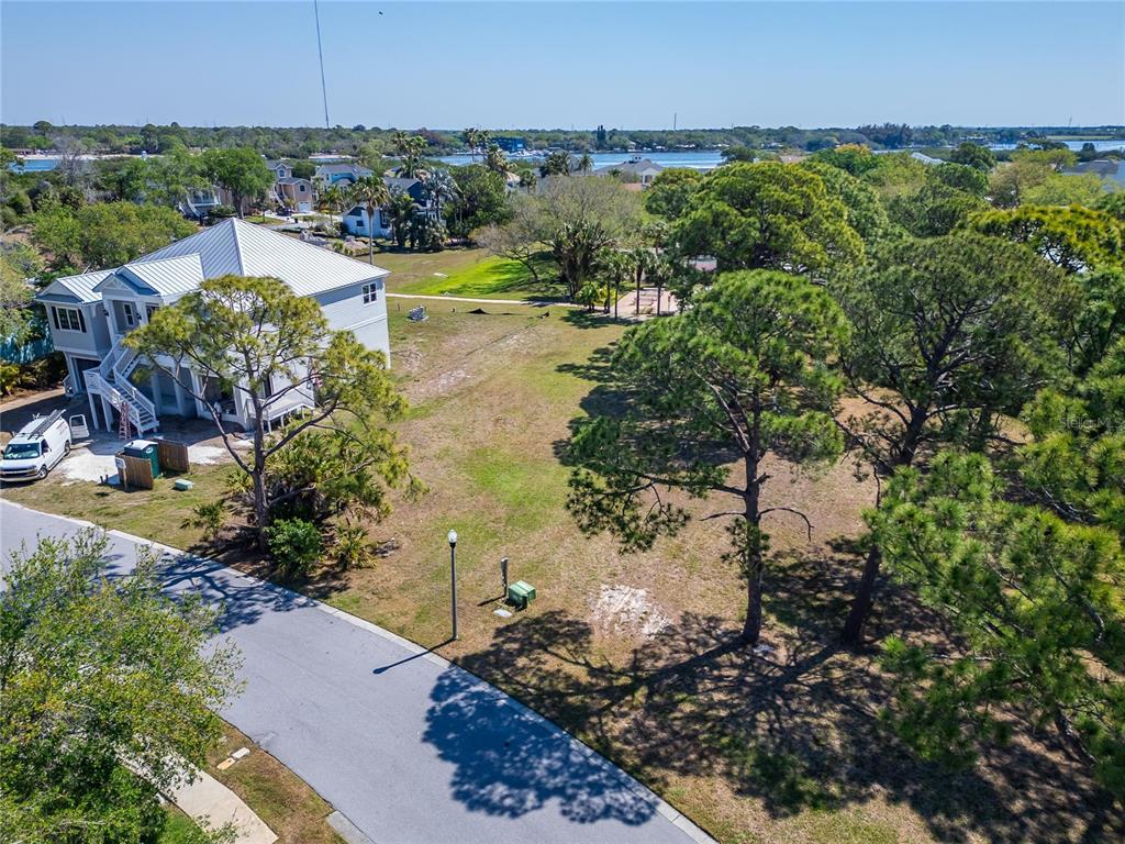 An aerial view shows a vacant grassy lot next to a multi-story house near water — HARBOUR WATCH DRIVE, TARPON SPRINGS, FL