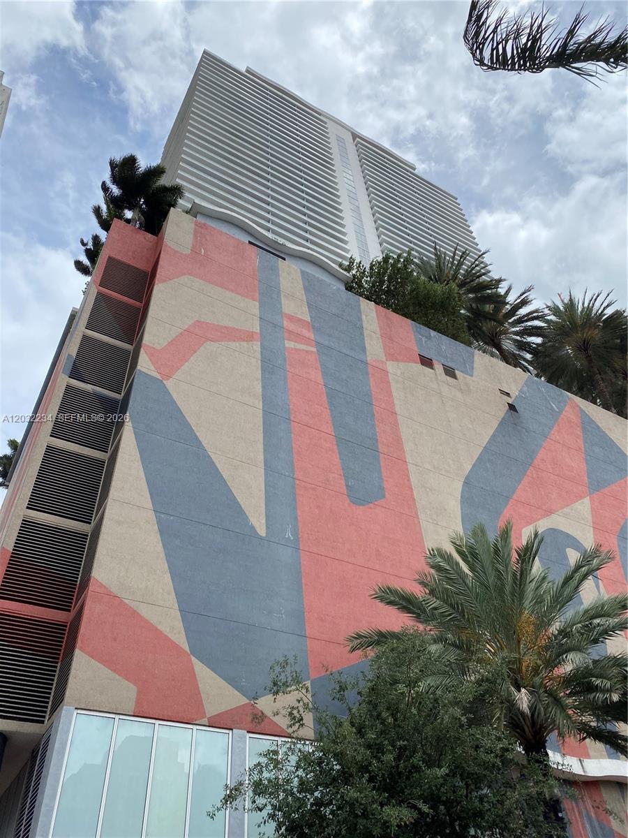 A low-angle exterior view of a high-rise building featuring a large geometric mural — 50 Biscayne Blvd # 2902, Miami FL 33132, MIAMI, FL