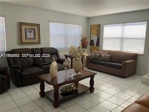 A living room with tile floors, a brown leather sofa, and a wooden coffee table — 1300 W 53rd St # 19, Hialeah FL 33012, HIALEAH, FL
