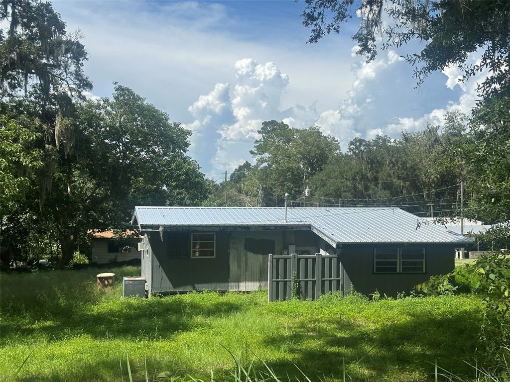 A single-story house with a metal roof and gray siding sits in a grassy lot — 1610 NE 14TH AVENUE, OCALA, FL