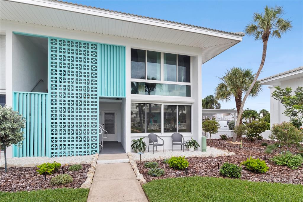 A two-story building exterior features a turquoise breeze block screen and large glass windows — 5400 GULF DRIVE UNIT 18, HOLMES BEACH, FL
