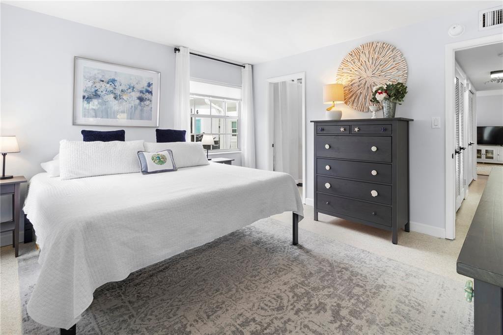 A bedroom features a king bed, a dark gray dresser, and a patterned area rug — 5400 GULF DRIVE UNIT 18, HOLMES BEACH, FL