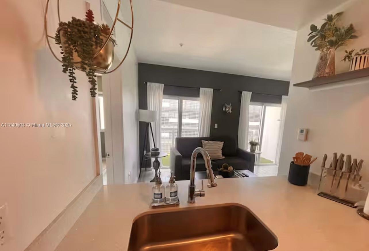 A kitchen sink and countertop overlook a living room with a sofa and patio doors — 481 NE 29th St # 705, Miami FL 33137, MIAMI, FL
