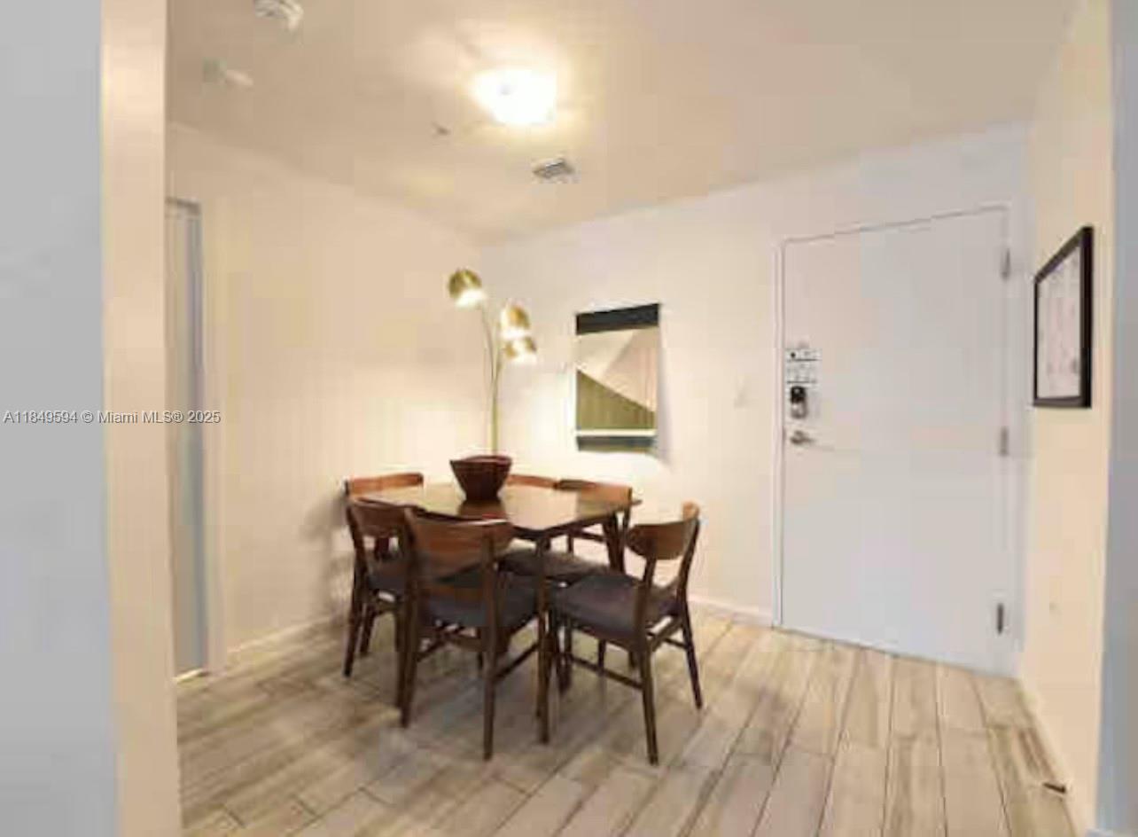 A dining area features a wooden table, four chairs, a floor lamp, and light-colored flooring — 481 NE 29th St # 705, Miami FL 33137, MIAMI, FL