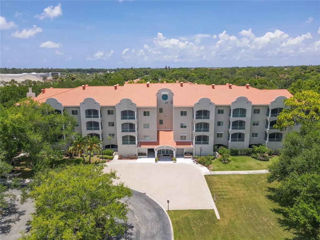 An aerial view of a multi-story apartment building with a terracotta tile roof — 3731 SARASOTA SQUARE BOULEVARD UNIT 309E, SARASOTA, FL