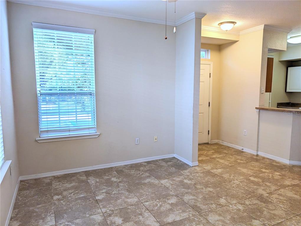 An empty room with beige walls, tile flooring, a window with blinds, and a doorway — 5711 SOLDIER CIRCLE UNIT # 102, SARASOTA, FL