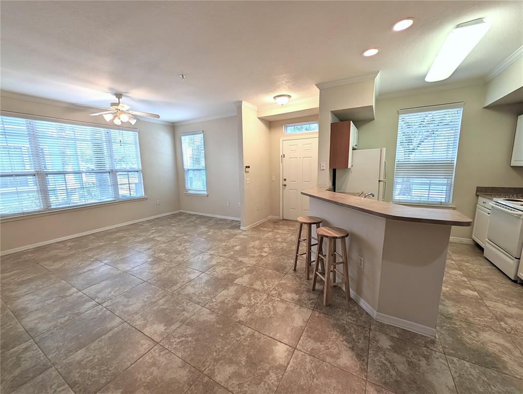 An open-concept kitchen and living area features tile flooring, a breakfast bar, and large windows — 5711 SOLDIER CIRCLE UNIT # 102, SARASOTA, FL