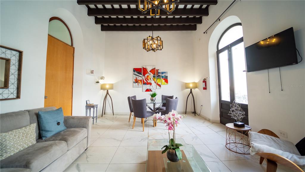 A living and dining room with high ceilings, exposed beams, tile floors, and modern decor — 101 SOL STREET UNIT 2B, OLD SAN JUAN, PR