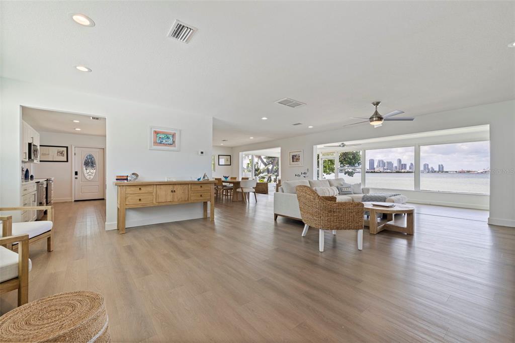 An open-concept living and dining area features light wood flooring, white cabinetry, and modern furniture — 501 22ND AVENUE SE, ST PETERSBURG, FL