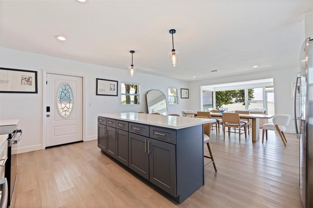A sunroom with light wood floors features large windows overlooking a bay and city skyline — 501 22ND AVENUE SE, ST PETERSBURG, FL