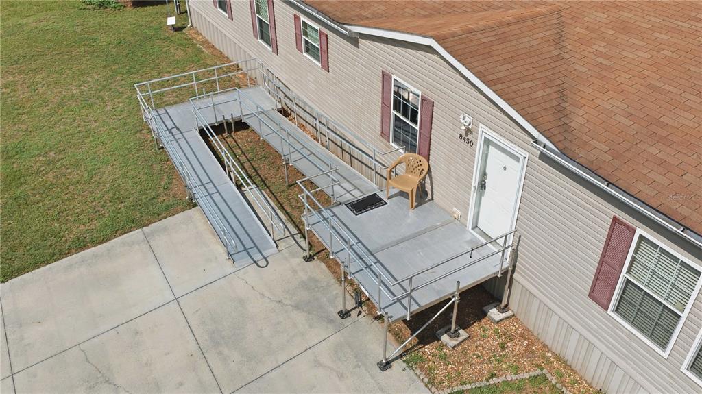 An elevated metal wheelchair ramp and deck are attached to the side of a mobile home — 8450 NW 15TH AVENUE, OCALA, FL