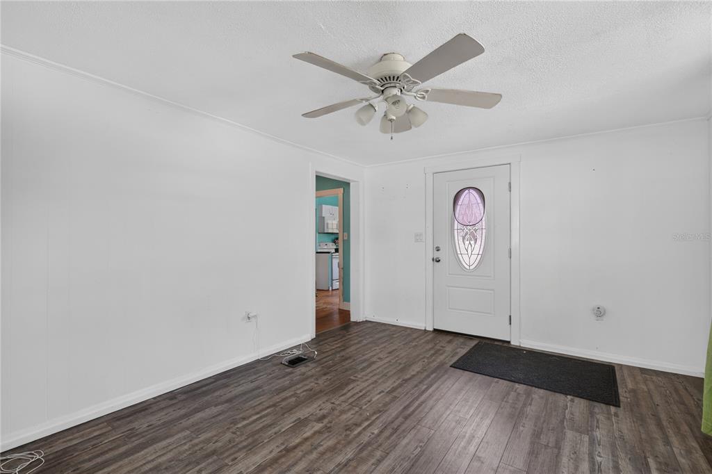A room with white walls, wood-look flooring, a ceiling fan, and a front door — 1311 SUMTER STREET, LEESBURG, FL