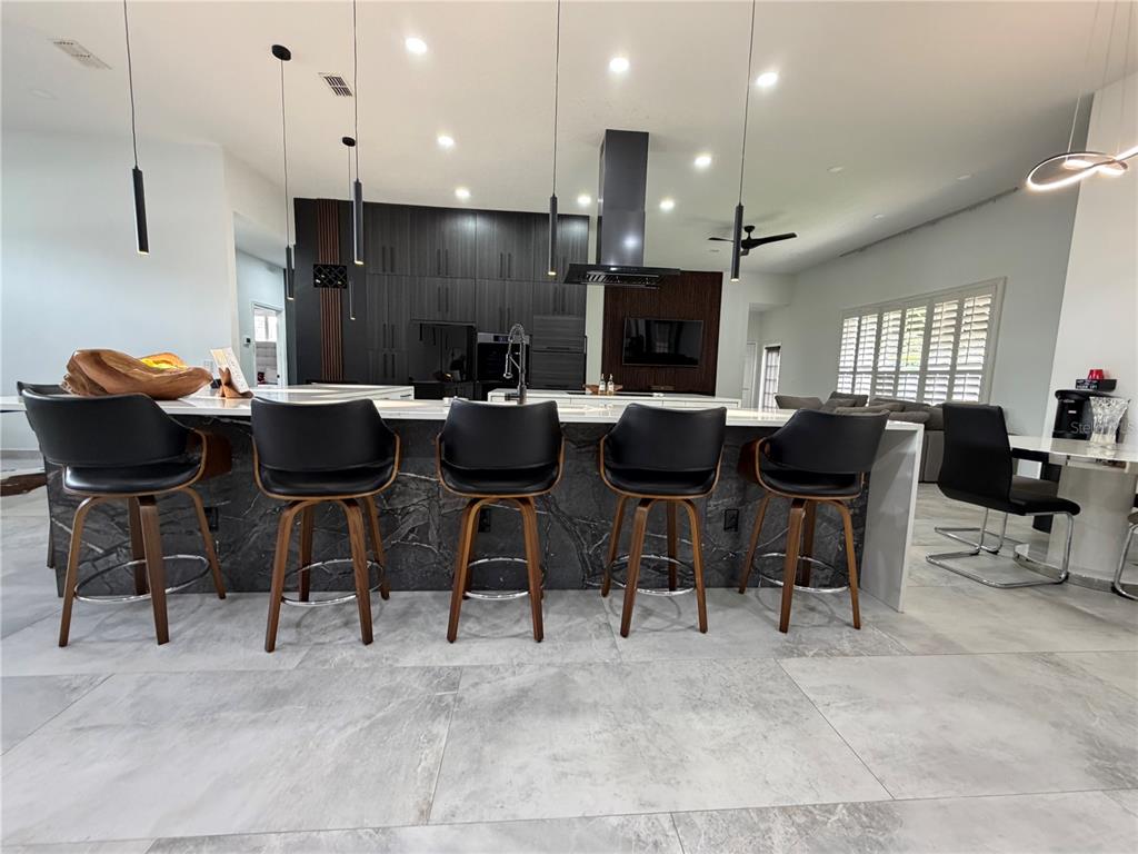 A modern kitchen features a large marble-faced island, black cabinetry, and bar stools — 4419 SADDLEWORTH CIRCLE, ORLANDO, FL