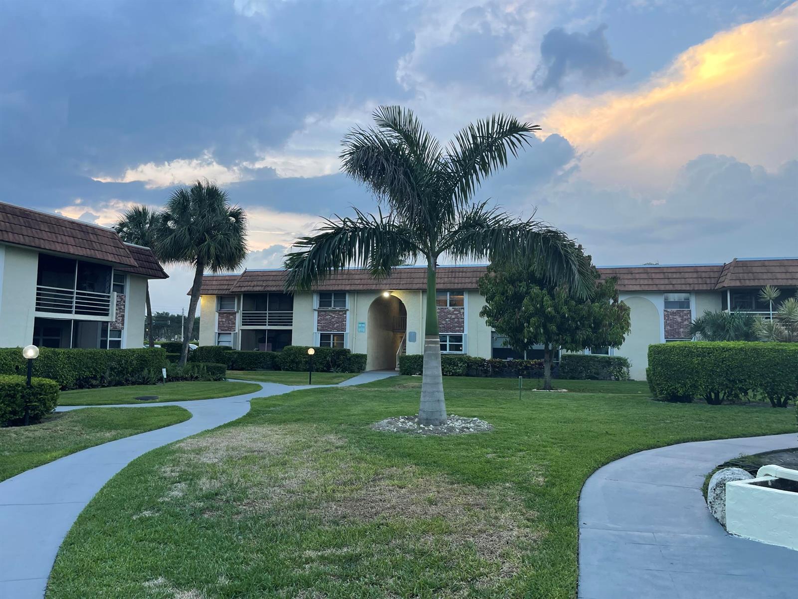 A two-story apartment building with a palm tree, manicured lawn, and paved walkways — 22735 SW 66th Avenue, Boca Raton FL 33428, BOCA RATON, FL