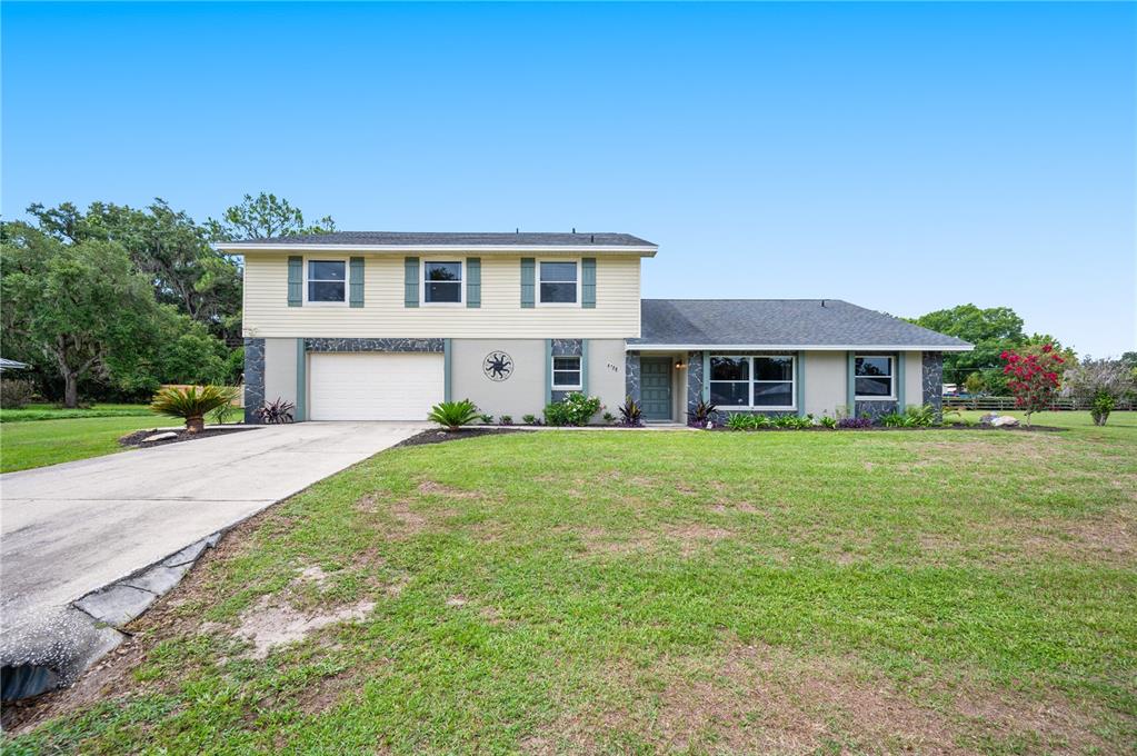 A two-story house with a beige upper level, gray lower level, and an attached garage — 4128 MATHER ROAD W, LAKELAND, FL