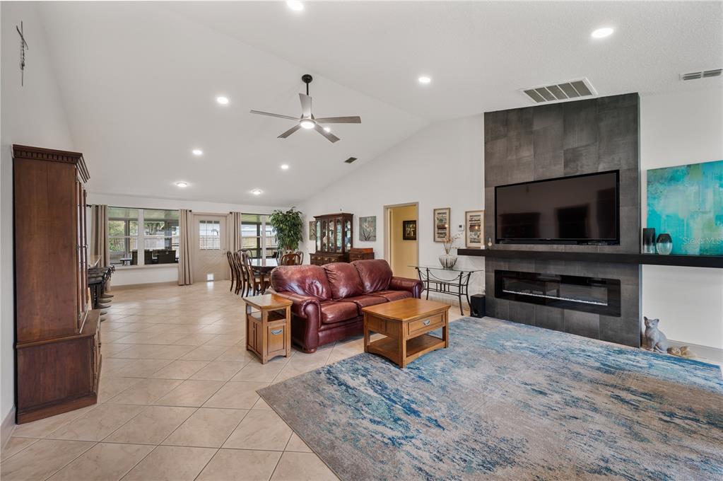 A living room features a tiled floor, a leather sofa, and a fireplace with tile — 4128 MATHER ROAD W, LAKELAND, FL