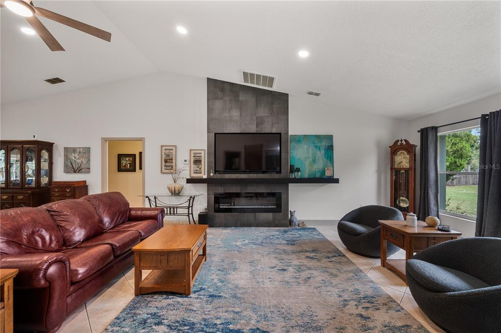A living room features a vaulted ceiling, a tiled fireplace wall, and a leather sofa — 4128 MATHER ROAD W, LAKELAND, FL