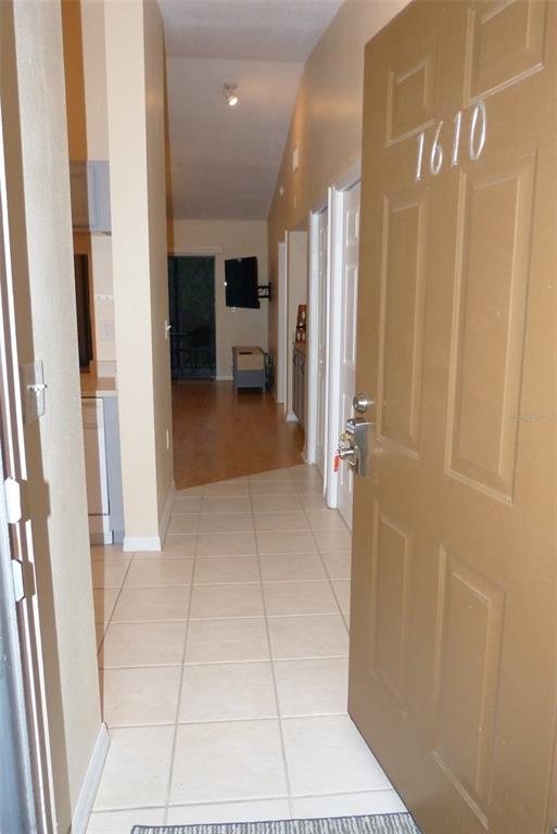 An open door reveals a tiled entryway leading to a living area with wood flooring — 1610 SEASCAPE CIRCLE UNIT 1610, TARPON SPRINGS, FL