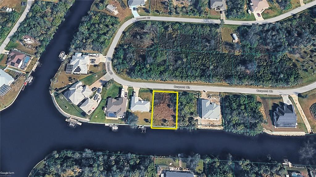 An aerial view shows a vacant, rectangular waterfront lot highlighted in yellow on a residential street — 12264 CORPORAL CIRCLE, PORT CHARLOTTE, FL