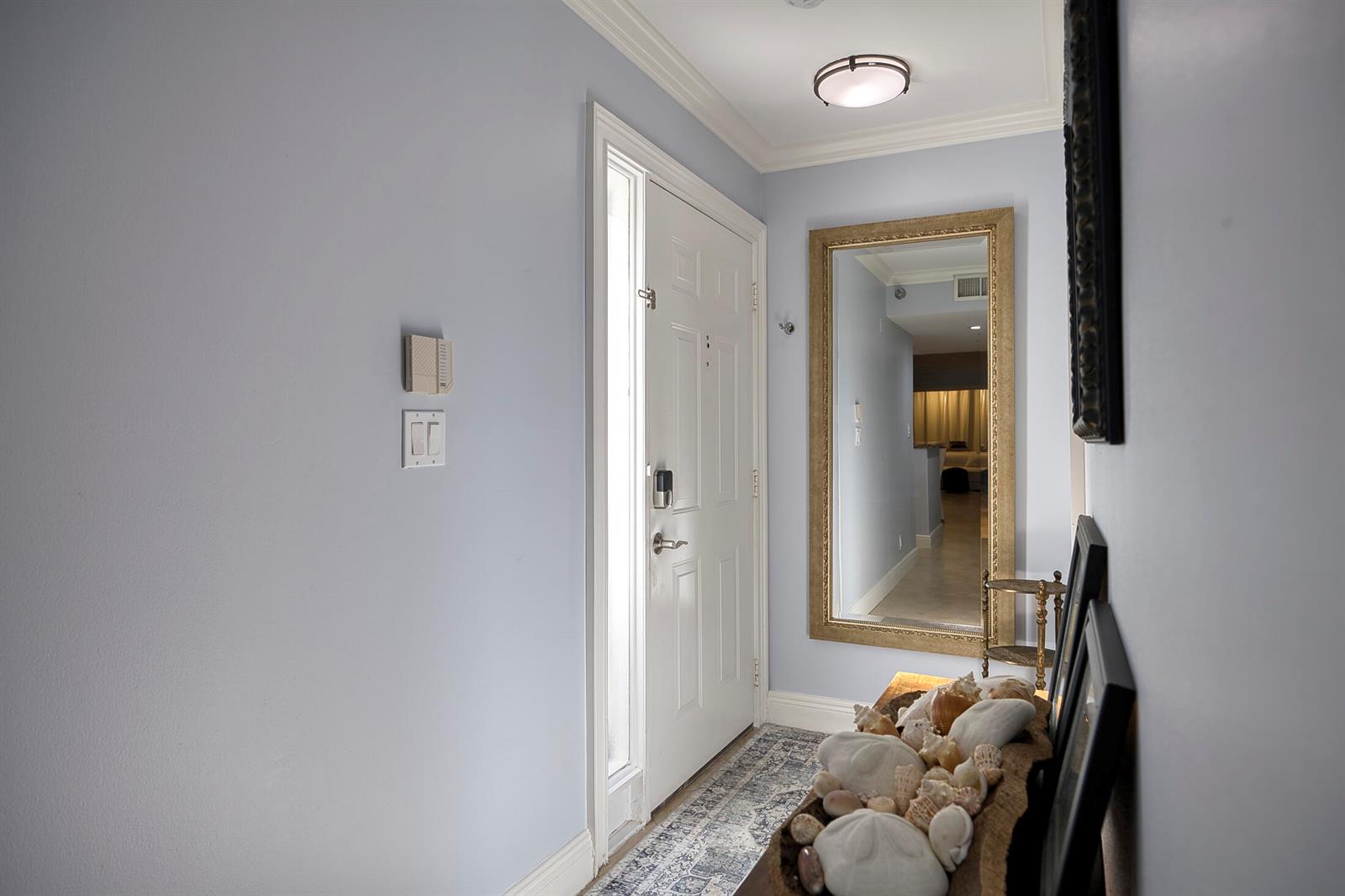 A light blue entryway features a white front door, a large gold-framed mirror, and decor — 380 NW 67th Street Apt 101, Boca Raton FL 33487, BOCA RATON, FL