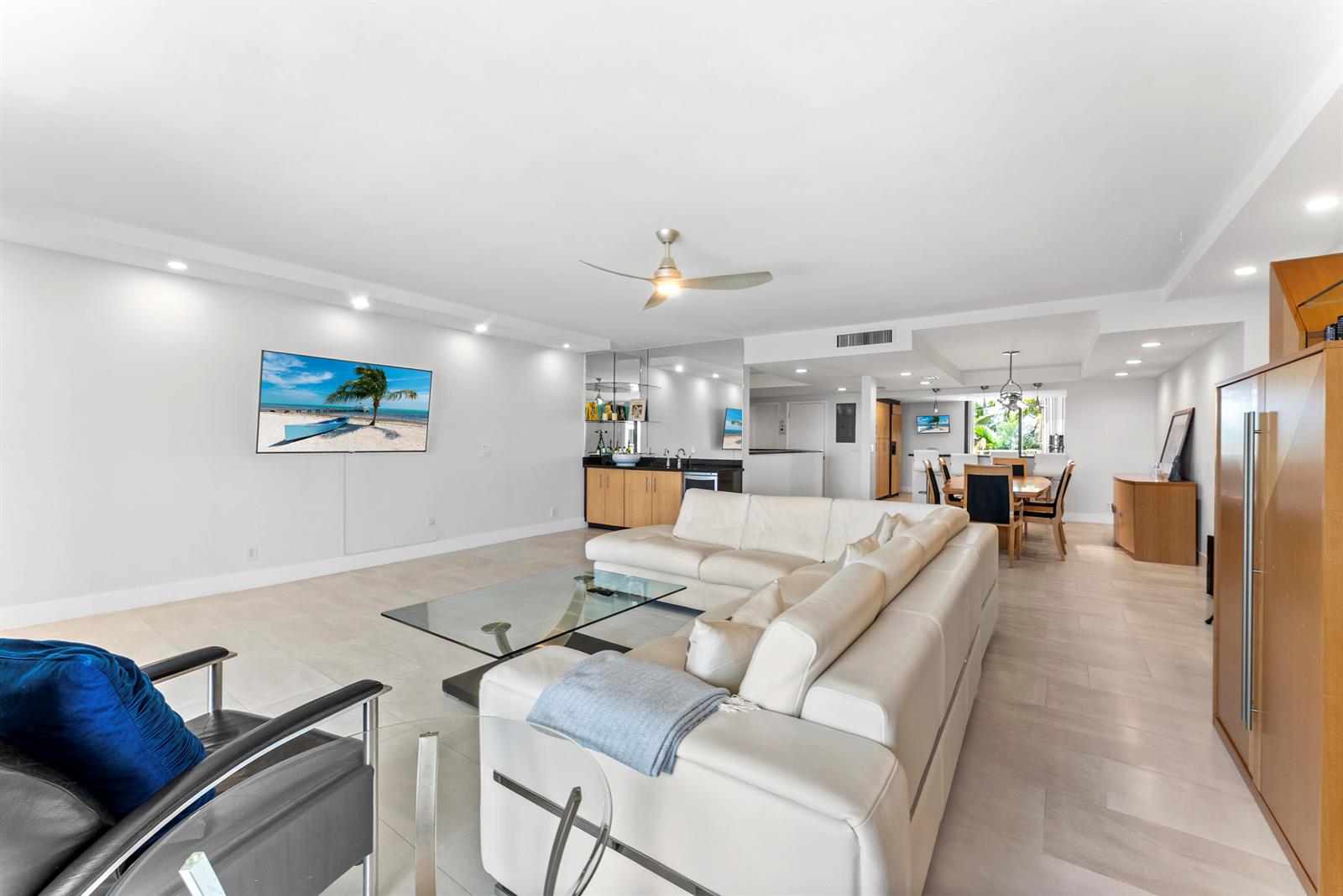 A spacious living room features a white sectional sofa, a glass coffee table, and a bar — 2155 S Ocean Boulevard # 11, Delray Beach FL 33483, DELRAY BEACH, FL