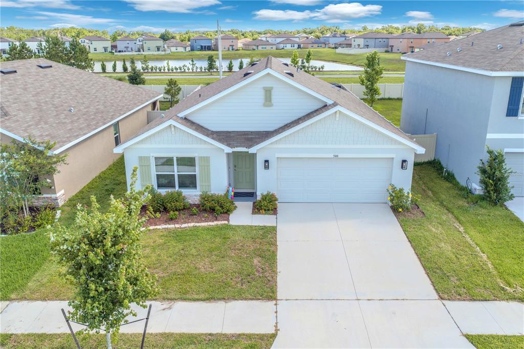 An aerial view of a single-story suburban house with a white garage and green door — 5166 PLUMERIA DRIVE, WIMAUMA, FL