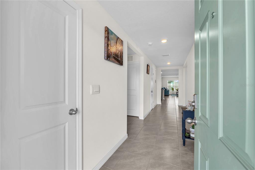 A view from an open teal front door into a tiled hallway with white walls — 5166 PLUMERIA DRIVE, WIMAUMA, FL