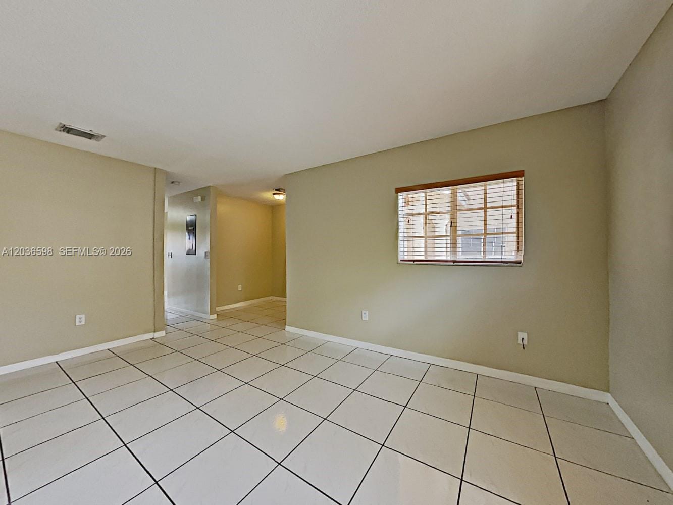 A room with light-colored tile flooring, beige walls, and a window with blinds — MIAMI, FL
