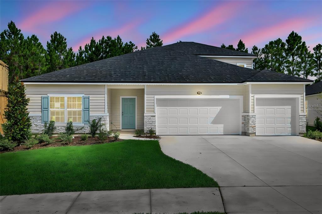 A single-story house with beige siding, stone accents, a three-car garage, and a teal front door — 3774 HOLSTEIN WAY, GREEN COVE SPRINGS, FL