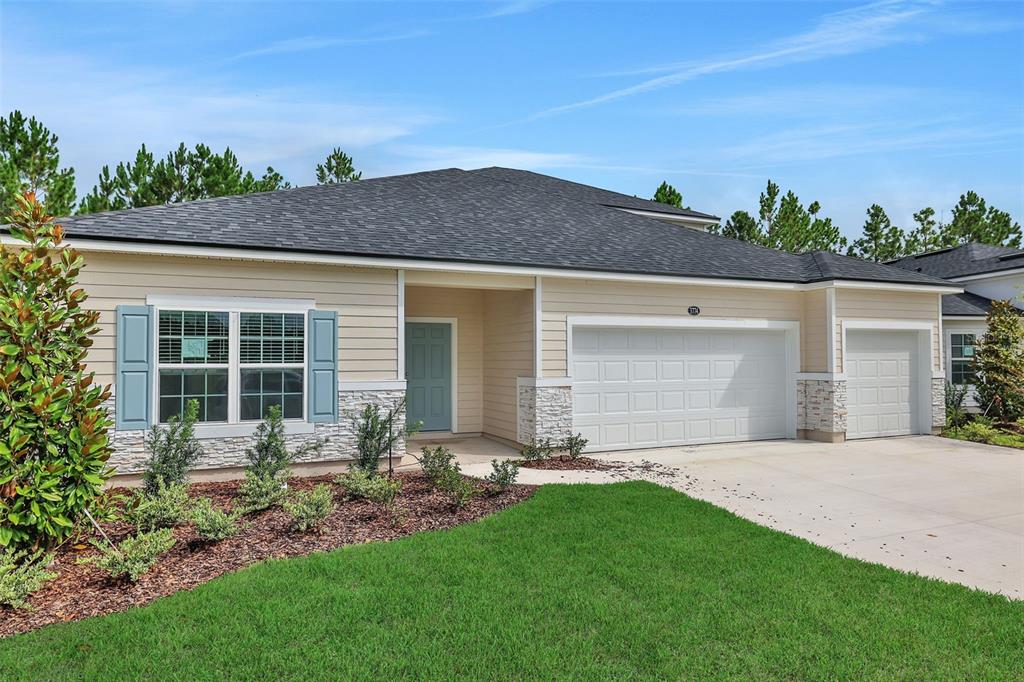 A single-story house with beige siding, a stone facade, and a three-car garage — 3774 HOLSTEIN WAY, GREEN COVE SPRINGS, FL