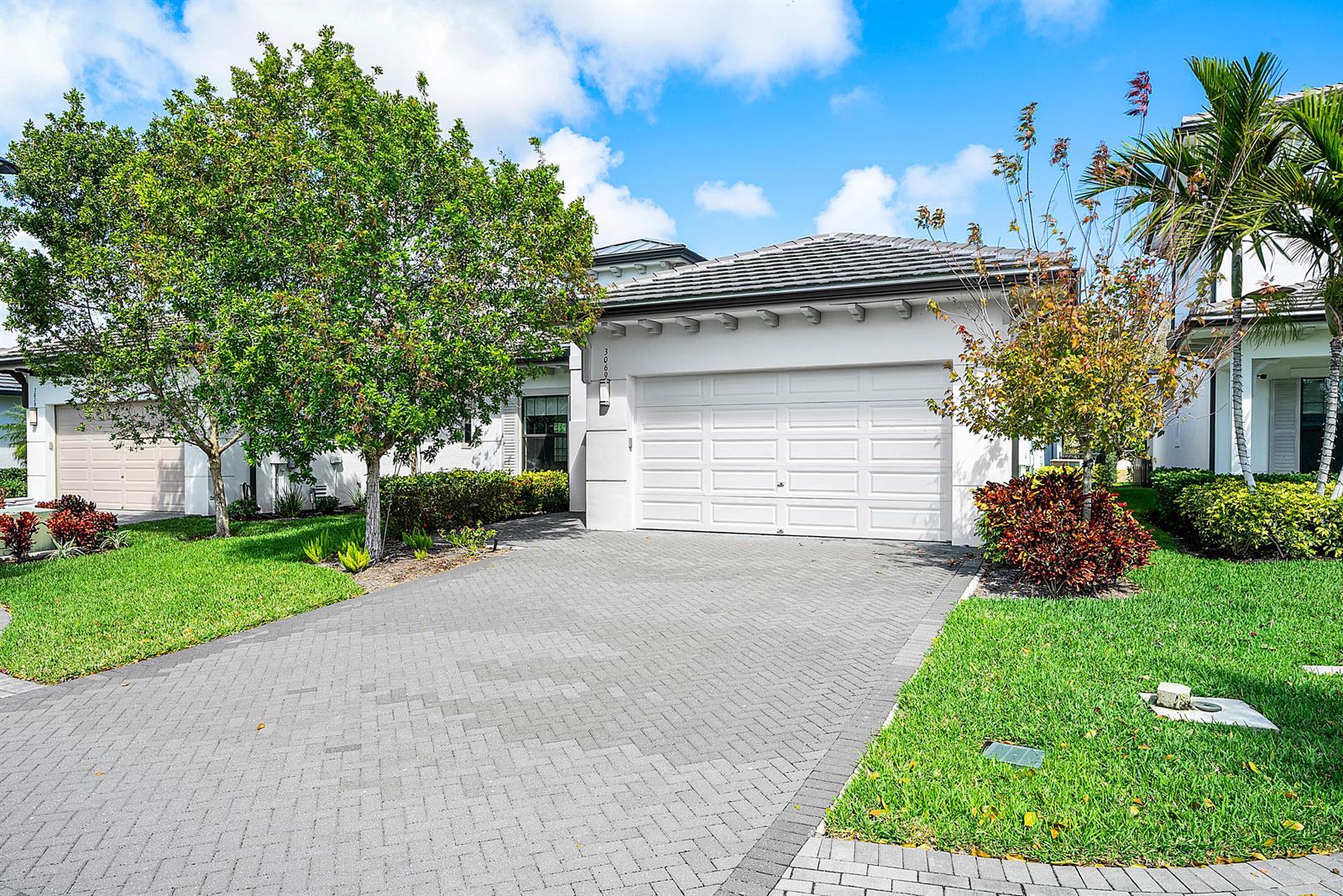 A white house with a gray tile roof, a paved driveway, and a two-car garage — 3069 Safflower Circle, West Palm Beach FL 33401, WEST PALM BEACH, FL