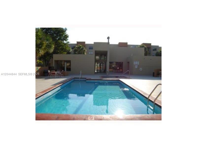 An outdoor swimming pool is situated in front of a multi-story apartment building — MIAMI, FL